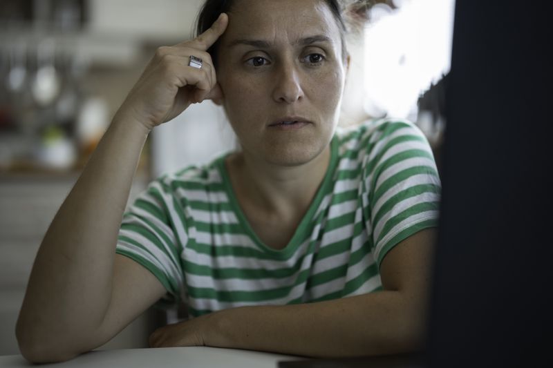 Woman staring thoughtfully at a computer monitor