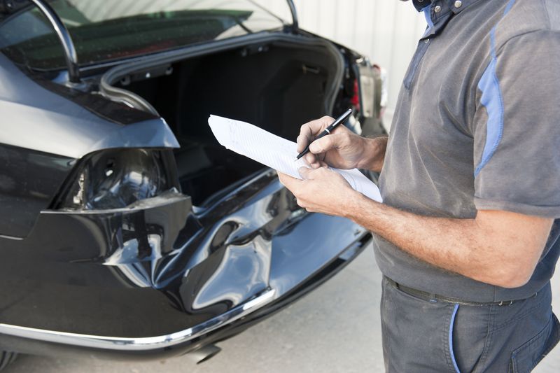 A person writing notes about a rear-ended black car after a crash