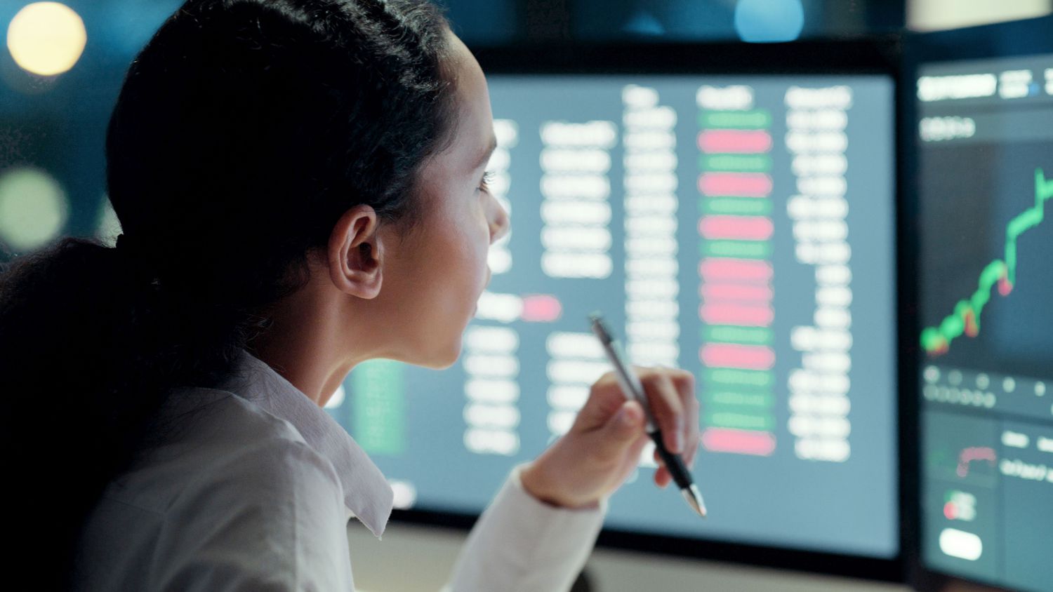 Woman staring at computer screens with stock market information displayed
