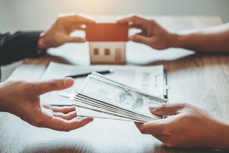 Cropped Hand Of Client Giving Money To Real Estate Agent At Office