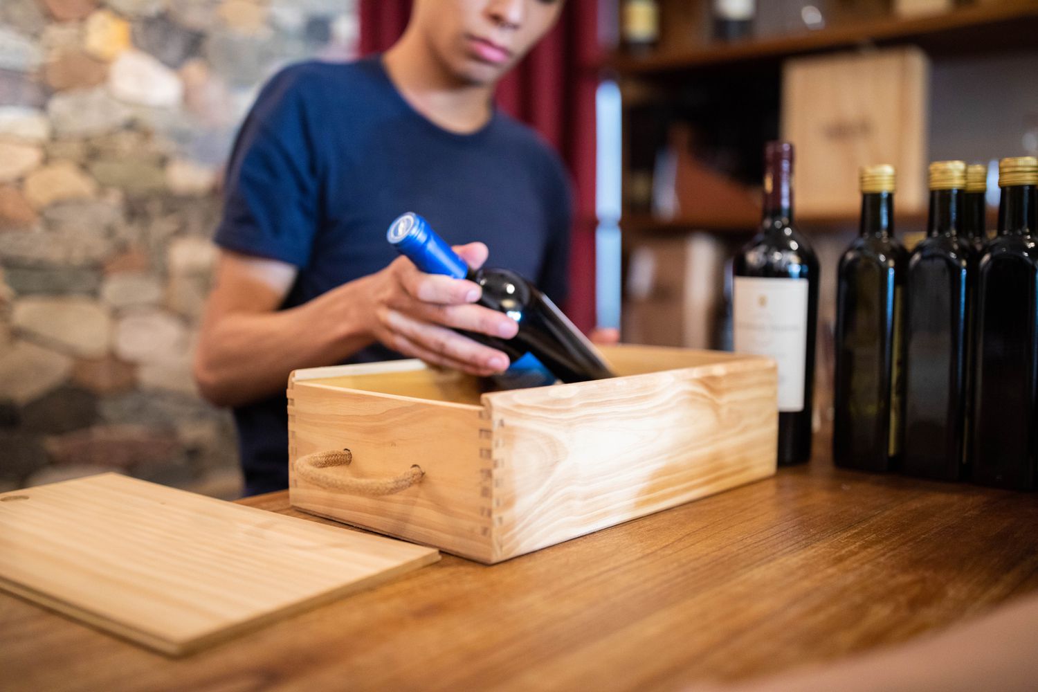 A person holds a bottle of wine that is based in a wooden box.