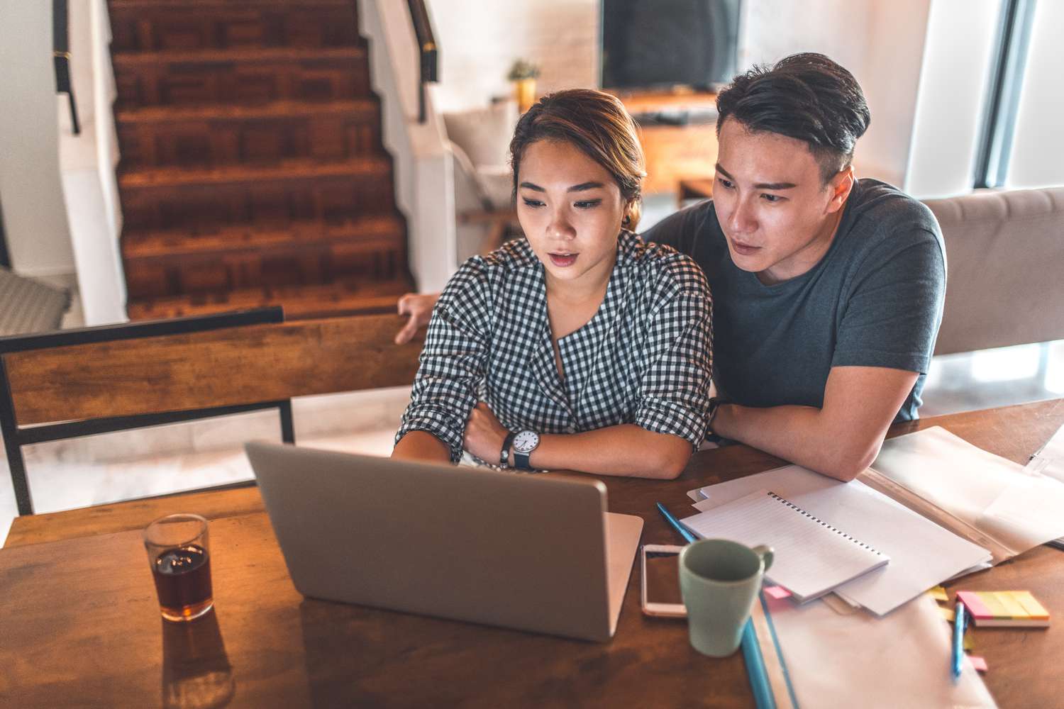 Serious young couple planning budget over laptop at table. 