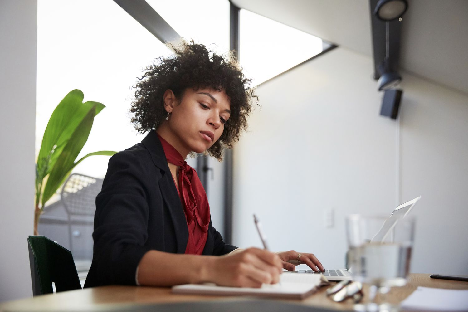 Woman sitting at a desk writing in a notepad.