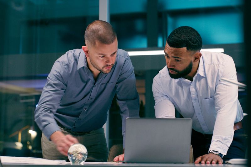 Two male investigators leaning over a computer.