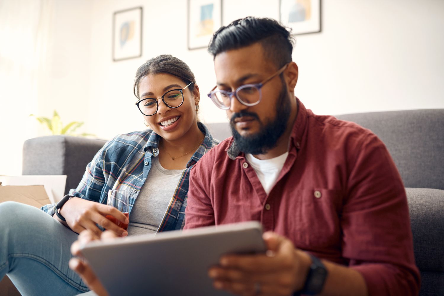 Young couple sitting on their sofa and looking at mortgage rates on a tablet