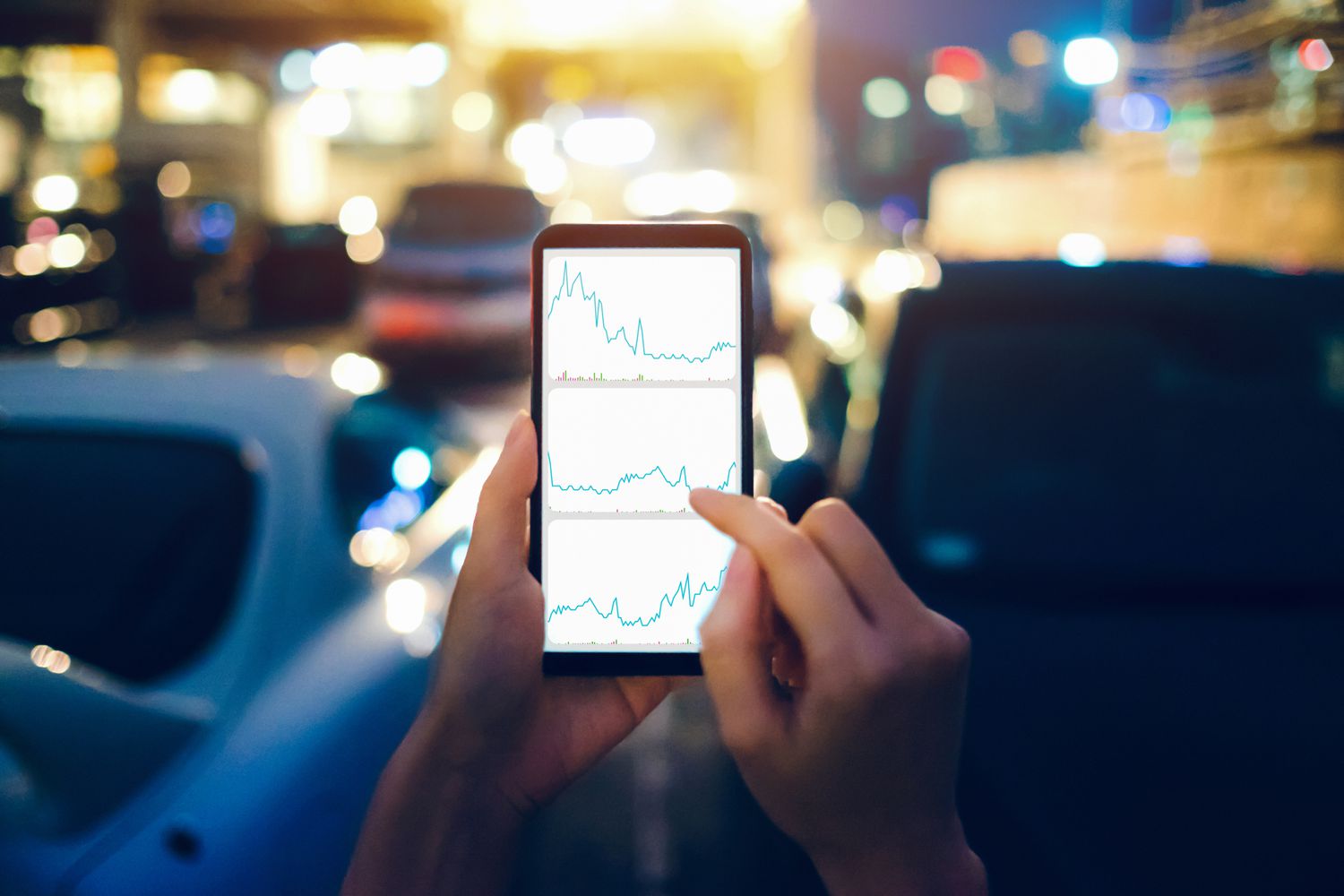 Human hands checking financial trading data on mobile phone while walking to car in parking lot