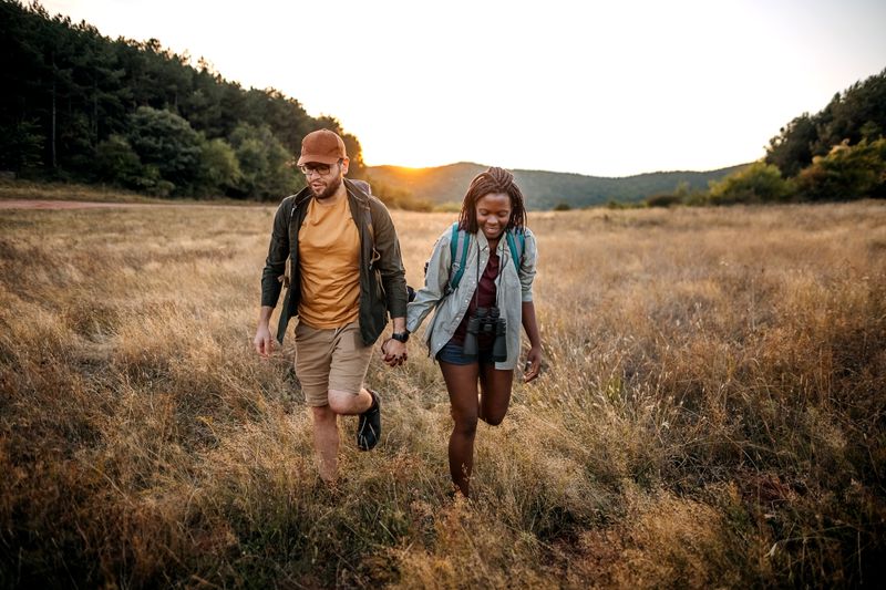 A couple in their thirties walks through nature at sunset.