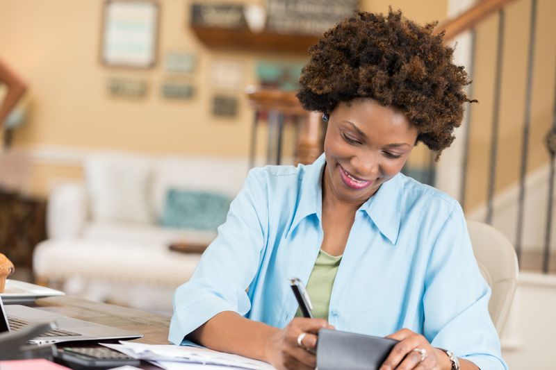 Woman sitting at a desk at home, writing a check to a charity