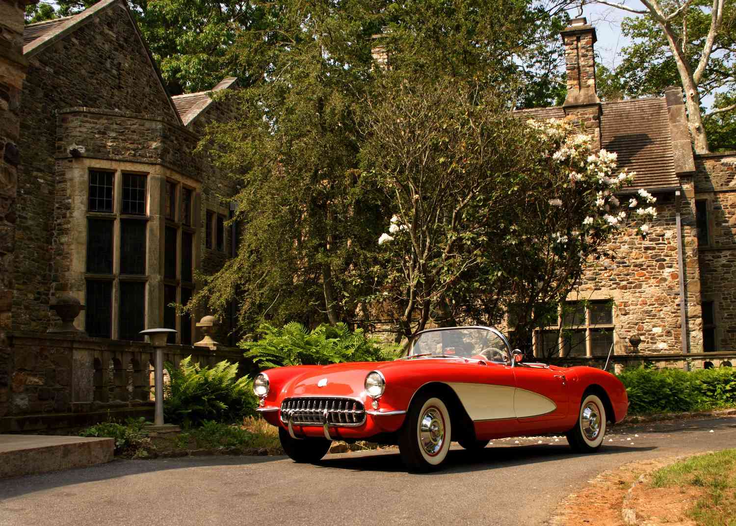 Classic car parked in front of stone mansion.