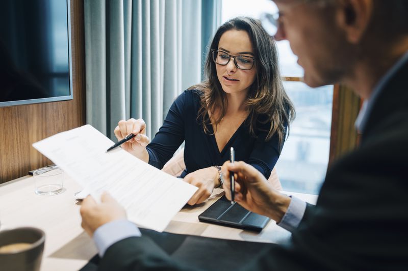 Two business executives review documents.