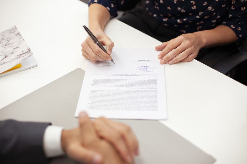 Borrower holding a pen to sign a loan agreement in order to get approved for a signature loan.