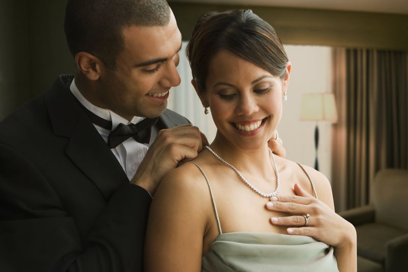 Man fastening wife's diamond necklace.