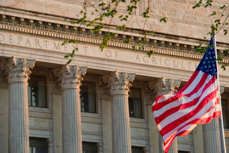 An American flag flaps in the wind in front of the U.S. Department of Agriculture building.