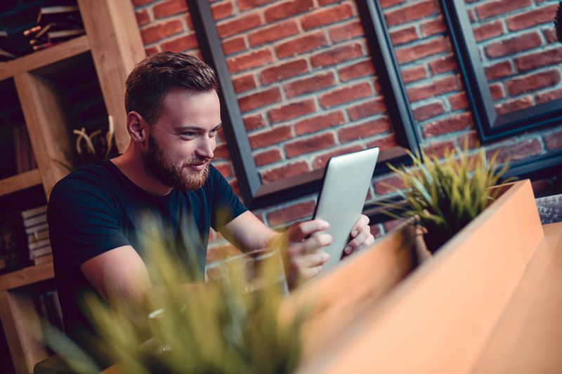 A man writing e-mail on digital tablet in cafe restaurant.