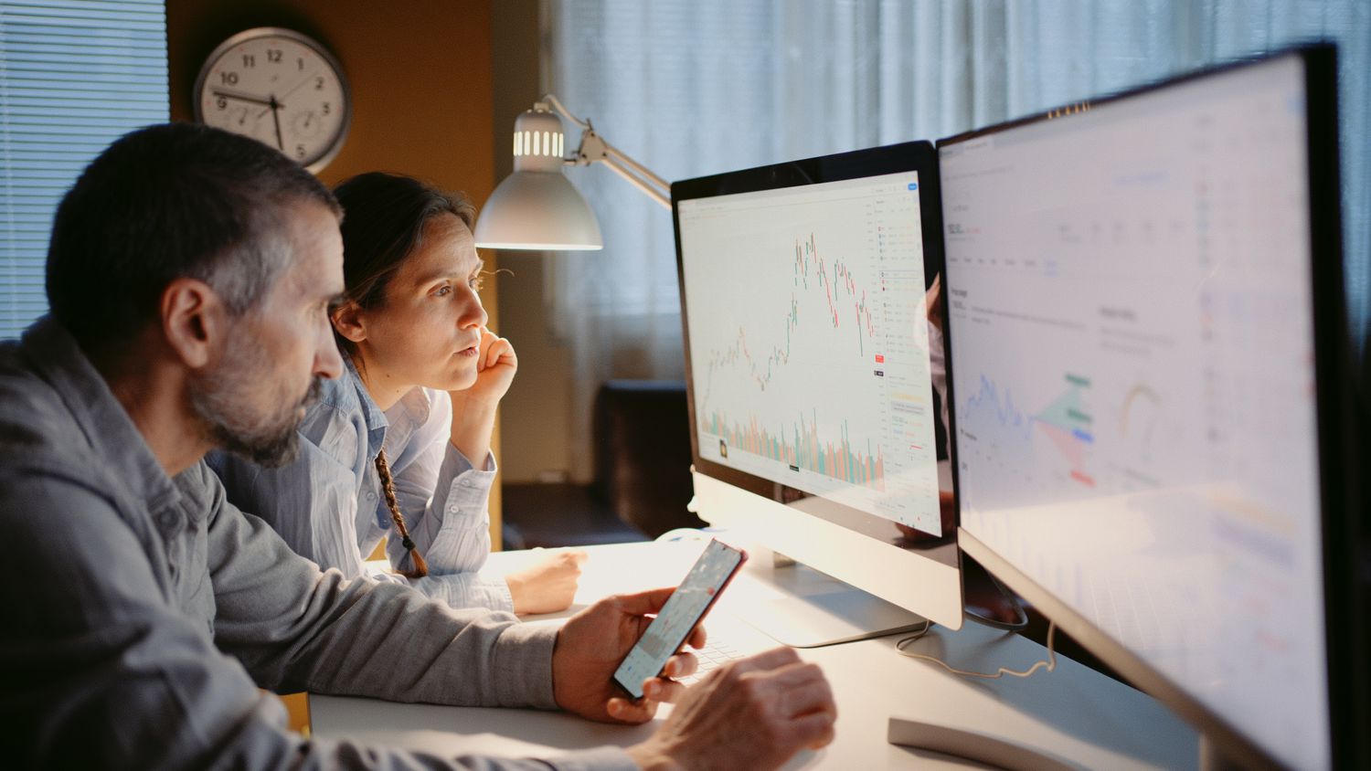 Two investors checking on their portfolio holdings in a home office.