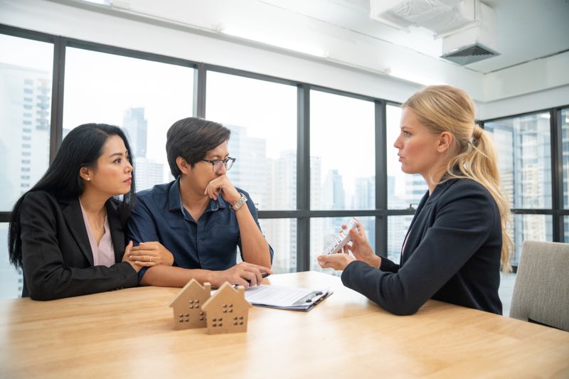 A young couple looks distressed when a realtor shows them how much they will clear from their house sell after capital gains tax rate is applied.