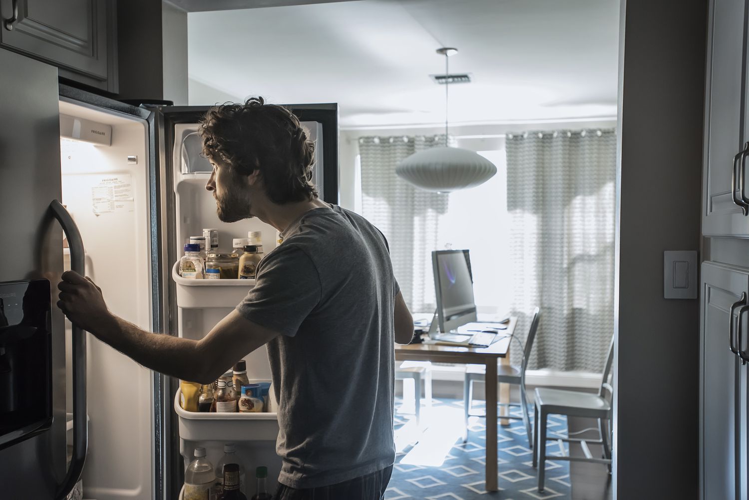 A man looks into his refrigerator.