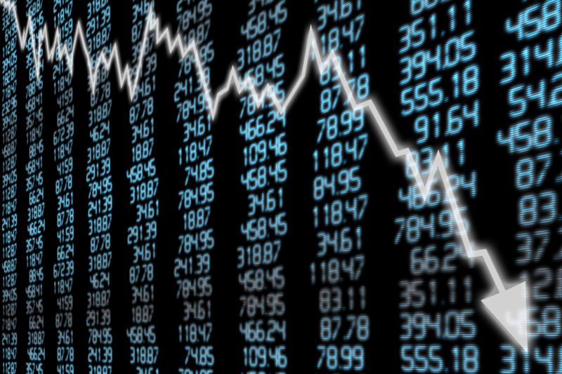 board of stock market prices with a white arrow over it going down