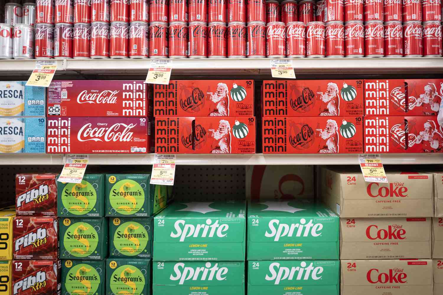 A variety of Coca-Cola products are seen on a grocery store shelf.