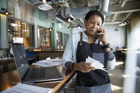 Female business owner paying bills in brewhouse