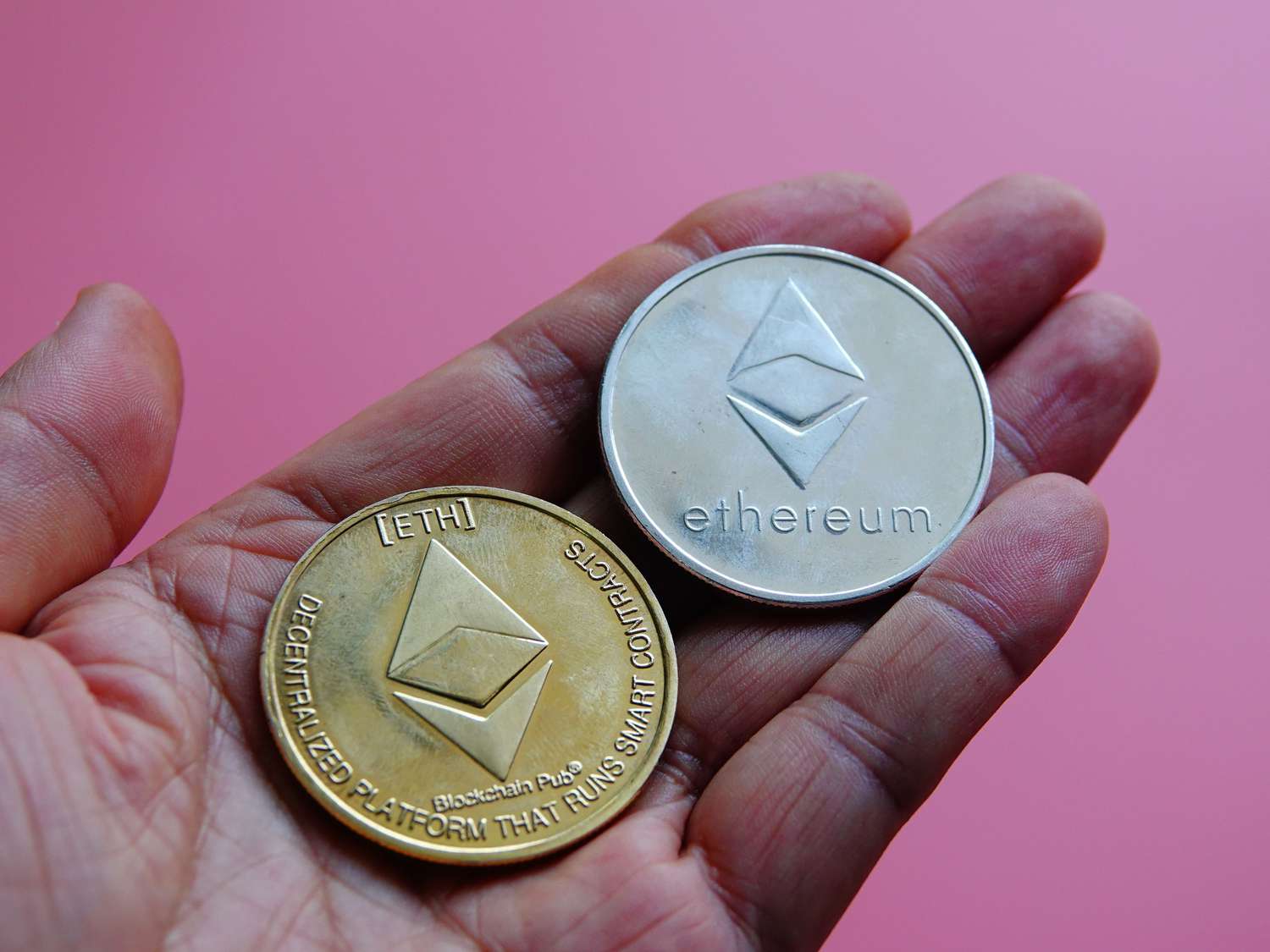 An investor holds in their hand two mock tokens of the blockchain-based Ethereum cryptocurrencies.