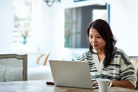 adult woman sitting at a table and looking at a computer in a home setting
