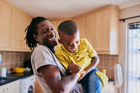 A parent holding their child in the kitchen