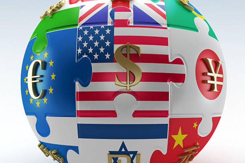 Countries' flags as puzzle parts with currency symbols on them mapped to a sphere representing the world economies
