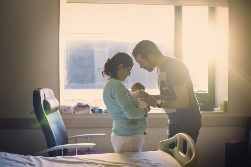 A couple hold a baby in the hospital.