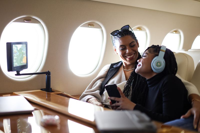 Woman and daughter setting next to each other on private jet. 