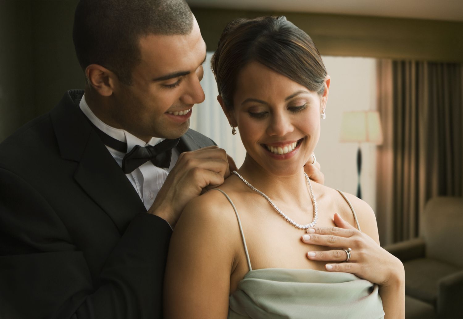 Man fastening wife's diamond necklace.