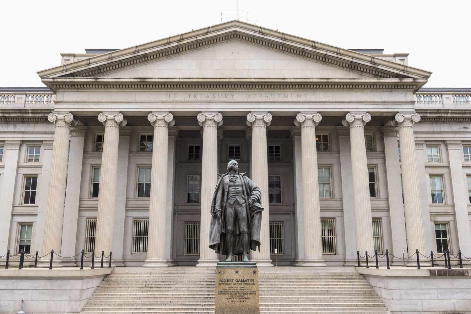 A view of the outside of the U.S. Treasury Department, with a statue in front.