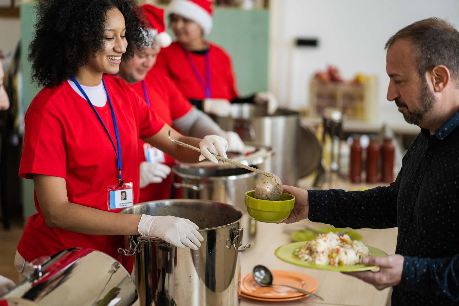 A volunteer ladles food into a man's bowl at a soup kitchen