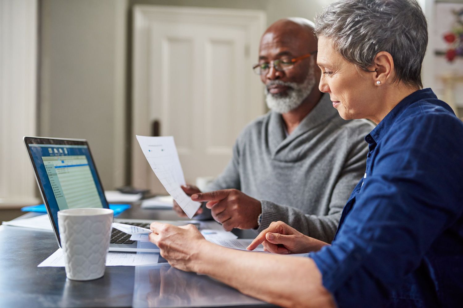 A couple looks at a piece of paper in front of a computer