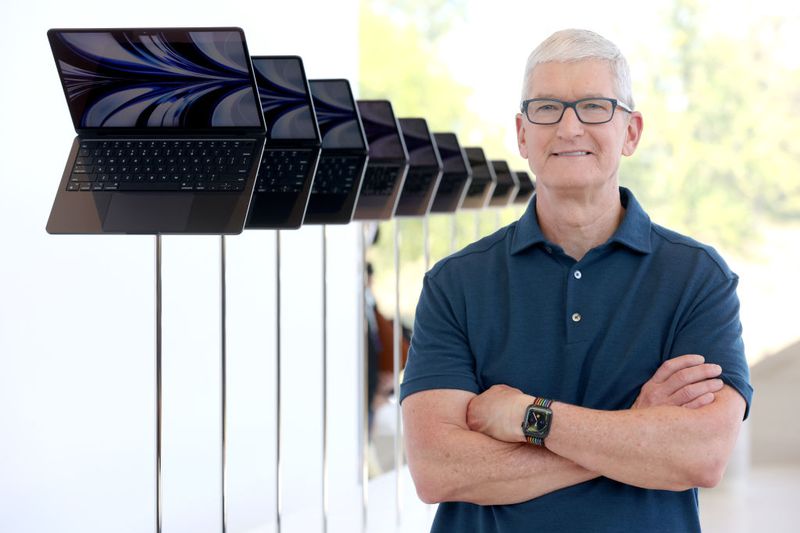 Portrait of Tim Cook next to Apple laptops