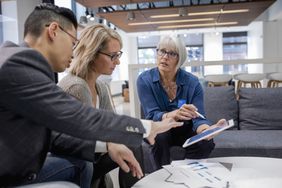 Loan manager with digital tablet meeting with couple in bank