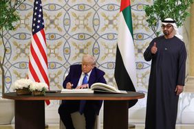 U.S. President Donald J. Trump signs the guestbook as UAE President Sheikh Mohamed bin Zayed Al Nahyan looks on.