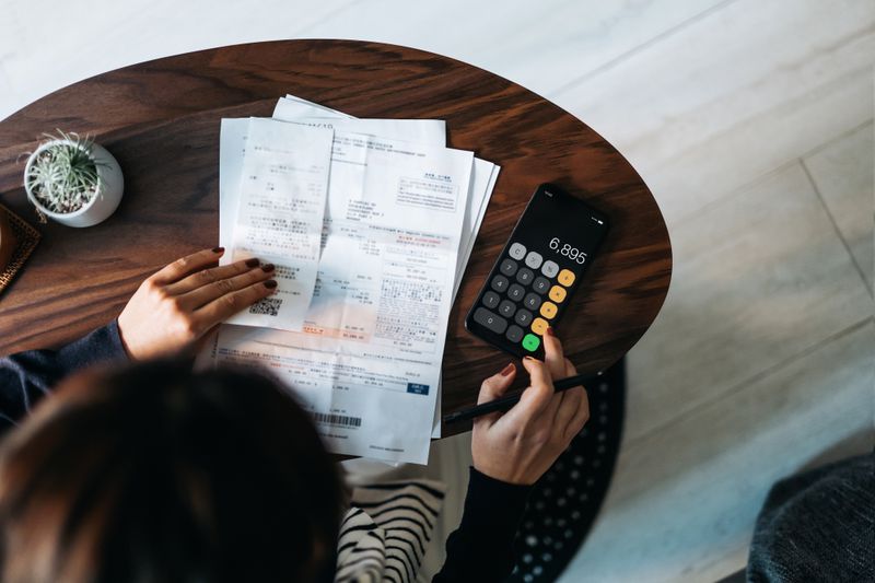 A woman looks over receipts while using a calculator