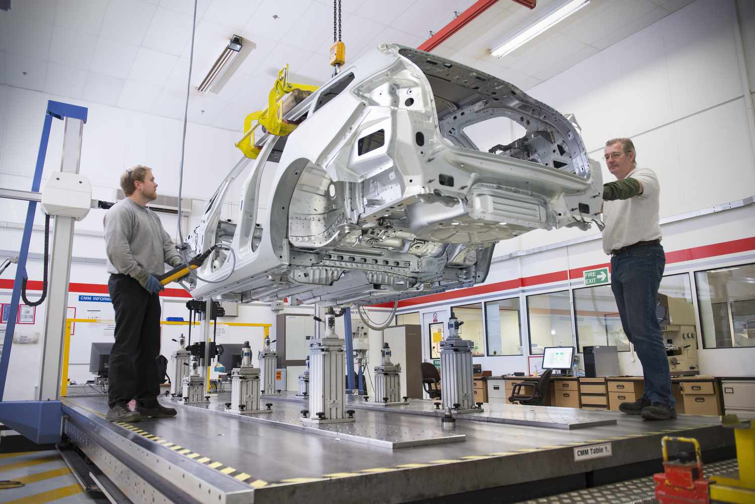 Two factory workers manufacturing a car