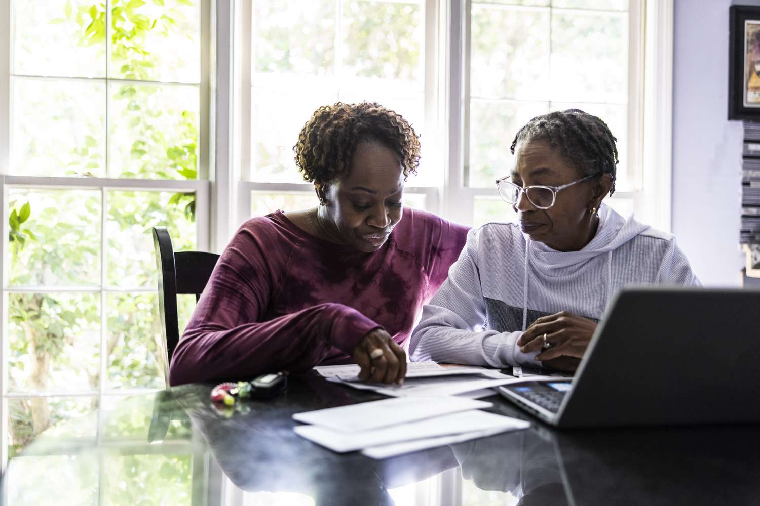 Lesbian couple paying bills and using laptop at kitchen table