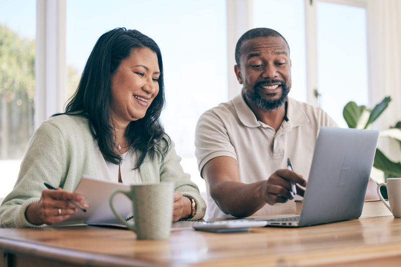 Couple in their 40s sitting at their dining room table and looking at mortgage rates online