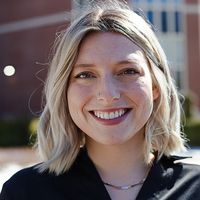 A woman with short blonde hair smiles for a headshot. 