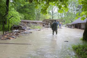 Desperate man standing in front of house in flood after a storm.