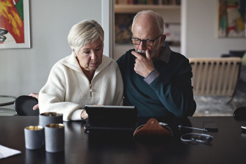 A man and a woman looking at a table at the dining room table