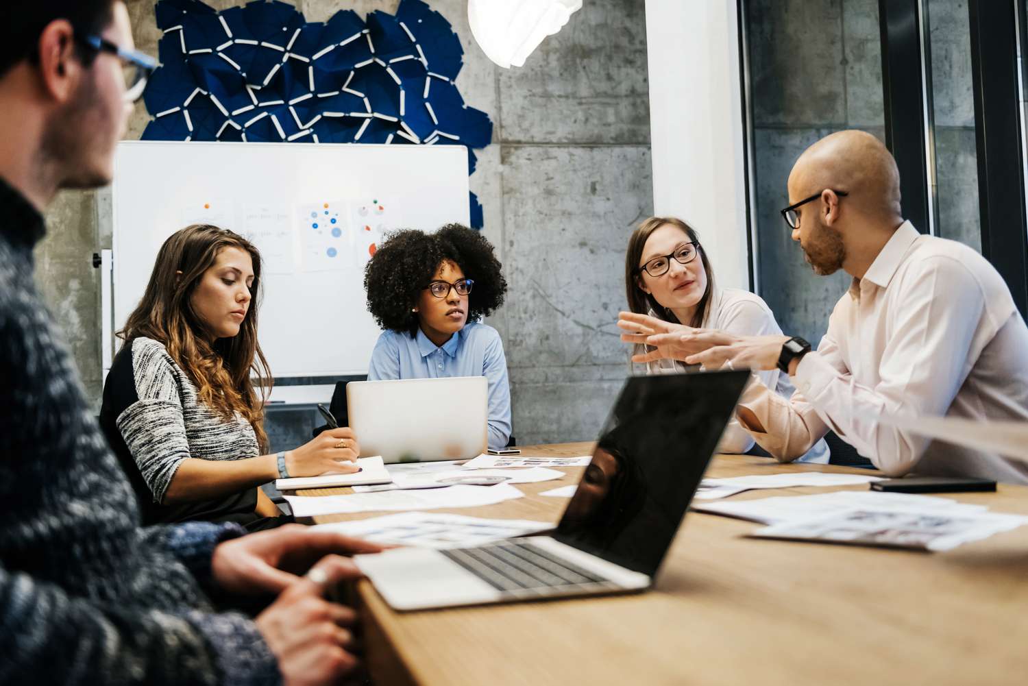 A group of adults have a discussion at an office table.
