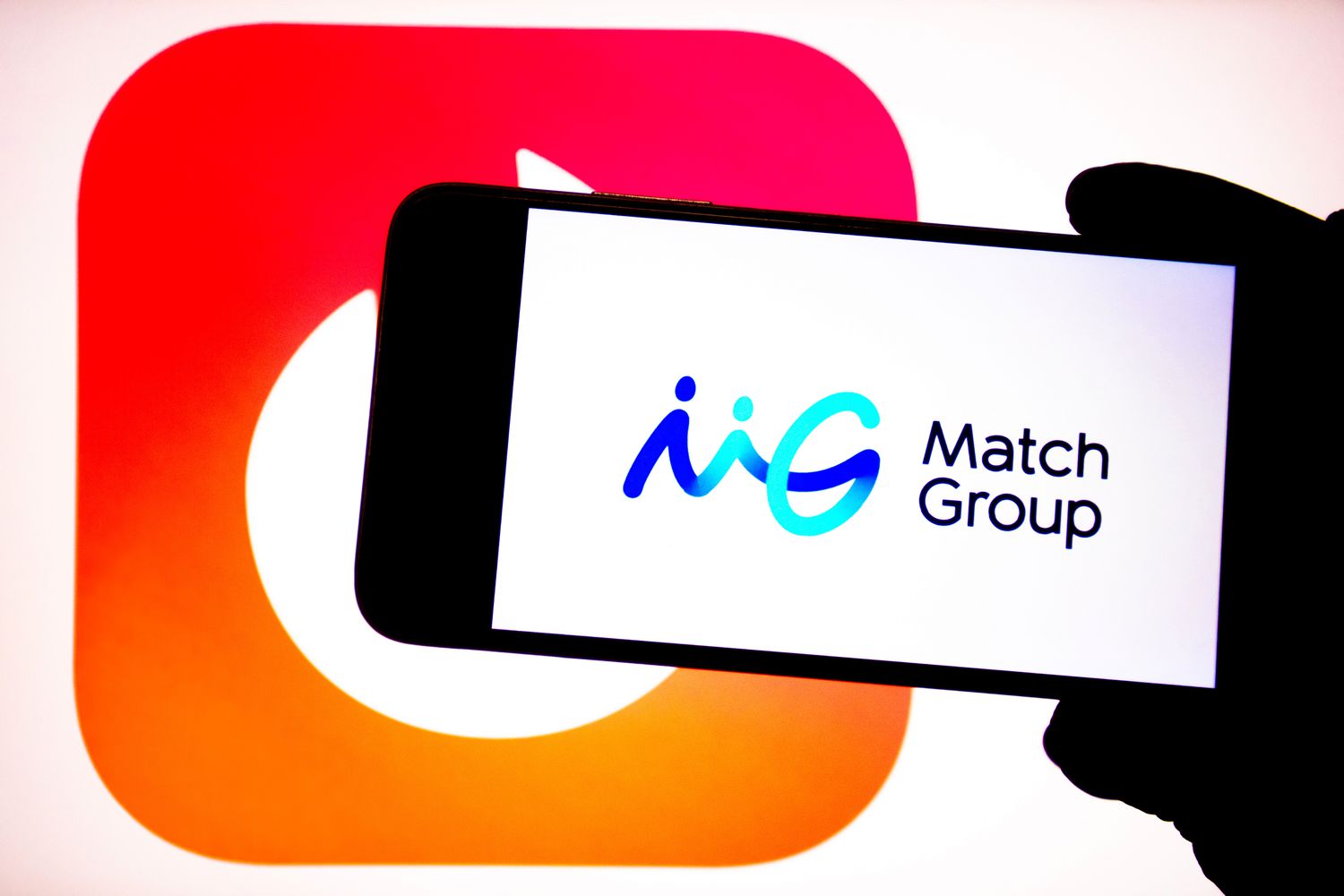 The Match Group logo is seen on a phone screen in front of a white background with the Tinder logo.