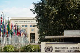 National flags hang limply from flagpoles in the still air outside of the United Nations headquarters in Geneva, Switerland.