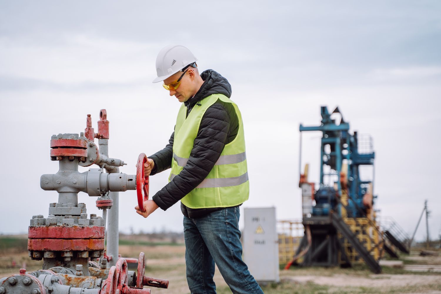 Man turning a crank at an oil and gas facility.