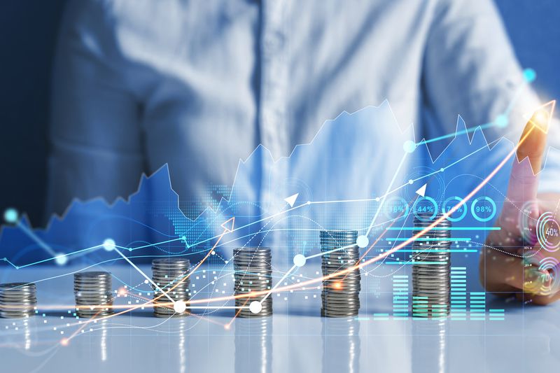 A person at a desk with an chart and stacked coins overlayed in the picture.