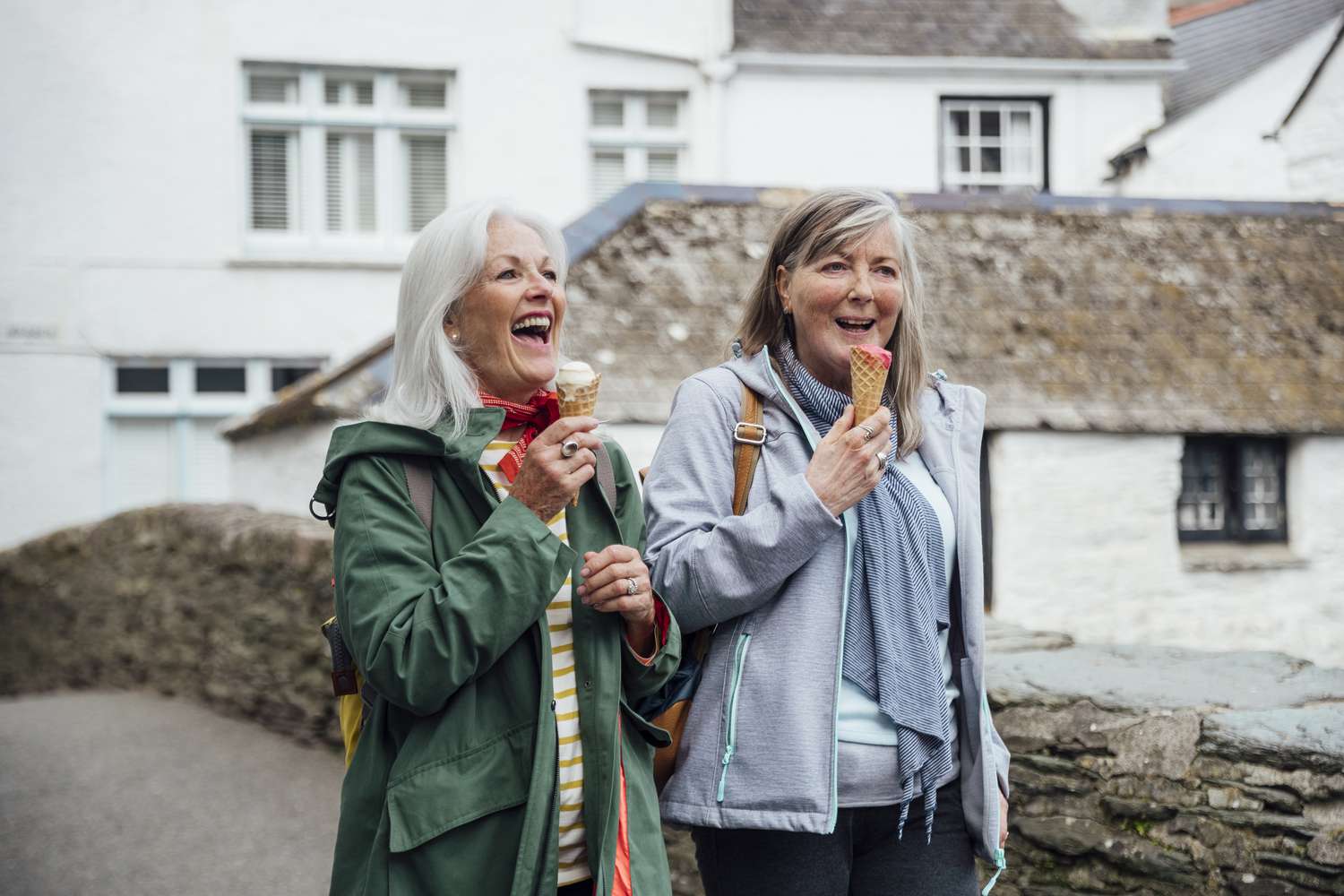 Two friends eat ice cream on a walk.